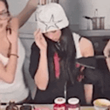a woman wearing a white hat is sitting at a table with a knife .