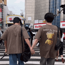 two people holding hands with one wearing a t-shirt that says acme de la vie