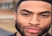 a close up of a man with a beard and pink lips making a funny face .