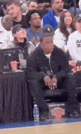 a man sits in the stands at a basketball game with a sign that says ny knicks
