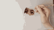 a hand is holding a brush in front of a white background that says made in animotica on it
