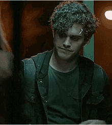 a man with curly hair is holding a piece of paper in his hands .