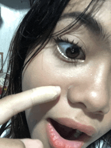 a close up of a woman 's face with a finger pointing at her nose