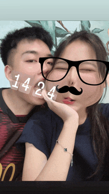 a man kisses a woman on the cheek with a fake mustache and glasses on