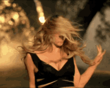 a woman in a black dress is dancing and her hair is blowing in the wind
