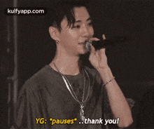 a young man is singing into a microphone and saying `` pauses `` .