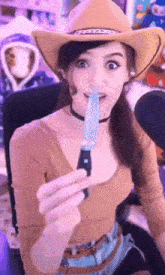 a woman wearing a cowboy hat is holding a blue object