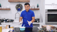 a man in a blue shirt is cooking in a kitchen with a jar of peanut butter on the counter