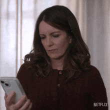 a woman in a red sweater is using a cell phone .