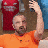 a man taking a selfie in front of a emirates shirt