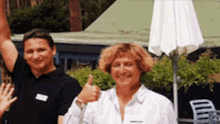 a man and a woman are standing next to each other giving a thumbs up sign .