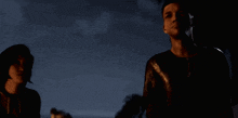 a man and a woman standing in the dark looking at something