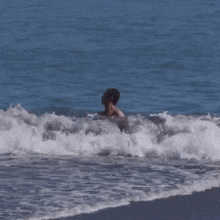 a shirtless man is swimming in the ocean waves