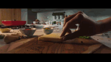 a person making a sandwich on a wooden cutting board