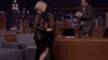 a man in a suit and tie is dancing with a woman in a black dress on the tonight show jimmy fall