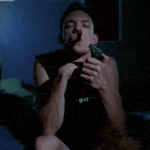 a man wearing a black shirt that says god is lighting up a cigarette