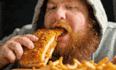 a man with a beard is eating a chicken sandwich