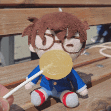 a stuffed toy with glasses is holding a lollipop in its mouth