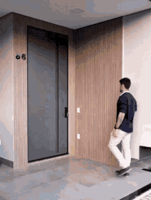 a man is standing in front of a door with the number 66 on it