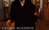 a man wearing headphones is standing in a hallway with the name callum mcgowan on the bottom right