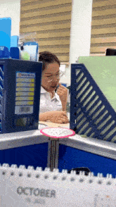 a woman sits at a desk with a calendar that says october on it