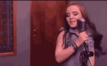 a woman is singing into a microphone while standing in front of a door .