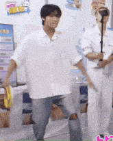 a man in a white shirt is dancing in front of a microphone while holding a tambourine .