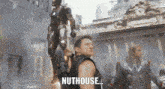 a man standing in front of a statue with the word nuthouse written on the bottom