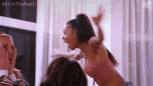 a woman in a pink bikini is screaming in the air while holding another woman 's hand .