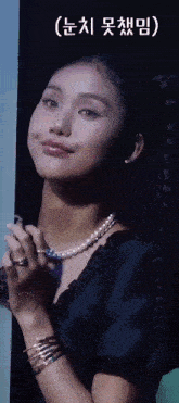 a woman wearing a pearl necklace and bracelets is standing in a dark room