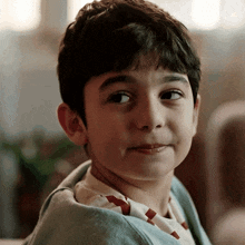 a close up of a young boy 's face with a blanket on his shoulders