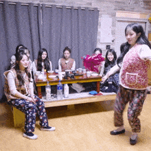 a woman in a pink vest is dancing in front of a group of women