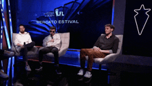 three men sit on a couch in front of a screen that says mercato estival