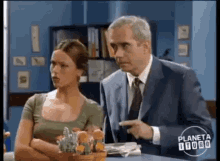 a man in a suit and tie points at a woman in a green shirt