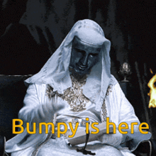 a man in a white robe is sitting in a chair with the words " bumpy is here " on the bottom