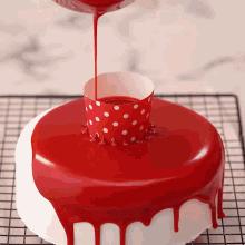 a cake with red frosting and a red polka dot cup