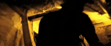 a person in a dark room with a yellow light behind them