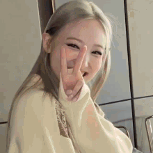 a close up of a woman giving a peace sign with her hands .