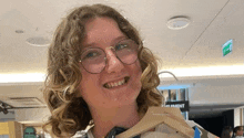a young woman wearing glasses is holding a wooden hanger in a store .