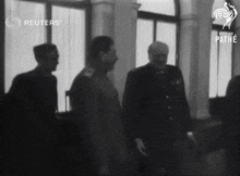 a group of men standing in front of a window with reuters written on the bottom left