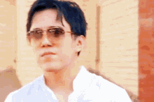 the man is wearing sunglasses and a white shirt .