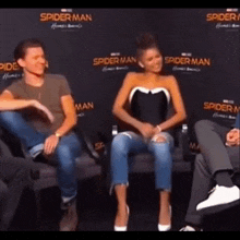 a man and a woman are sitting next to each other on a couch in front of a spider man sign .