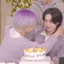 two men are hugging each other in front of a birthday cake .