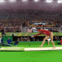 a female gymnast is doing a trick on a mat in front of a crowd
