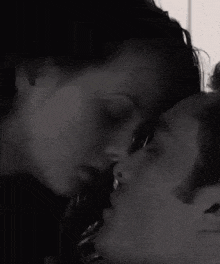 a black and white photo of a man and woman kissing