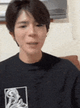 a young man wearing a black shirt with a picture of a statue on it