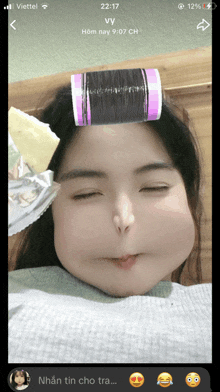 a woman with curlers in her hair is making a face on a phone screen