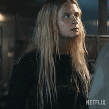 a woman with long blonde hair and a black shirt with netflix written on it