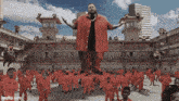 a large man in a red suit stands in front of a crowd of people