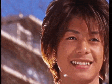 a close up of a young man 's face smiling with a building in the background .